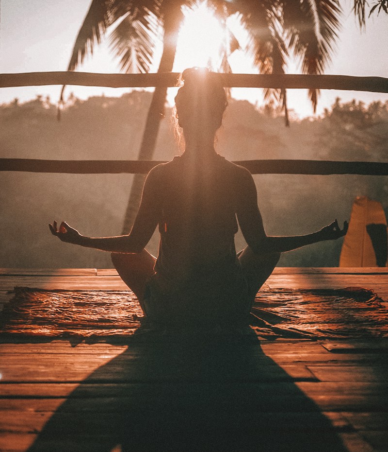 A woman meditating at sunrise