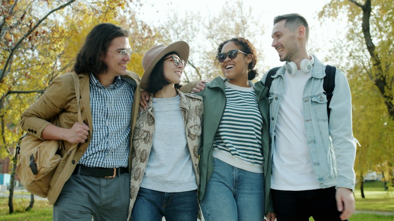 Four friends walking together in an autumn park